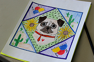 Ms. B's paper quilt square has a dog and some cactus with some flowers